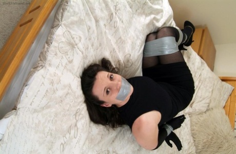 Fully clothed woman is bound and silenced with duct tape on her bed 46264281