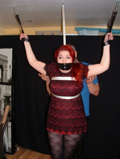 Pale redhead is silenced with a gag while restrained by her wrists in clothes 67881082