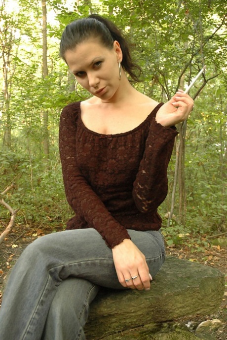 Brunette chick bares her boobs while smoking in the woods 27823780