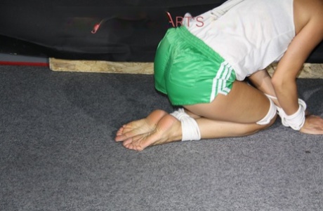 White girl is fitted with a gag while bound in shiny nylon gym shorts 20716980