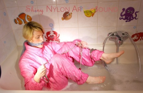 Blonde girl is left alone in a tub of bathwater while restrained in nylon wear 88594020