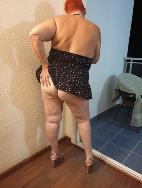 Fat nan with short red hair presses her big boobs and butt up against glass 42358050