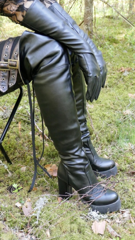 Clothed female wears leather gloves and boots plus shades in the woods 13335275
