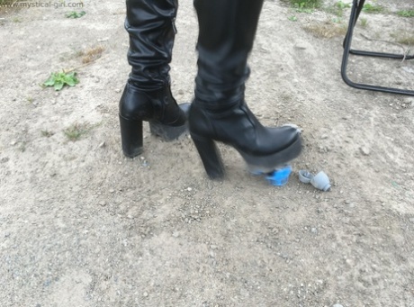 Unknown female crosses a dinky toy into the ground with black leather boots 31847698