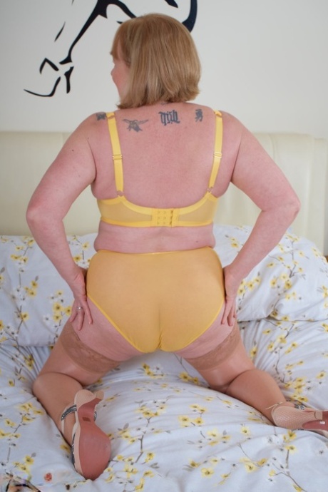 Mature British amateur Speedy Bee fingers her pussy on a bed in tan stockings 98047507
