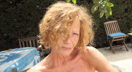 Redheaded granny Anne Swinger plays with her pussy while topless on a patio 12772783