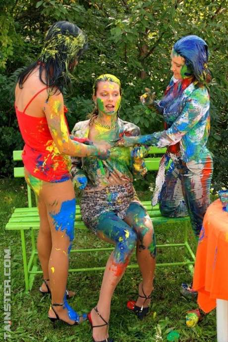 Clothed women cover themselves in finger paint on a garden bench 46496150